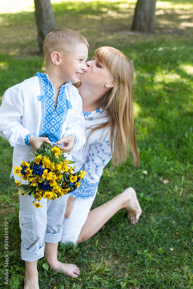 Fototapeta premium mother and son in embroidered shirts. national clothes of Ukraine. a boy gives flowers to his mother
