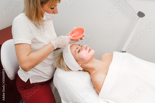 Cosmetologist applies a mask on the face of the client