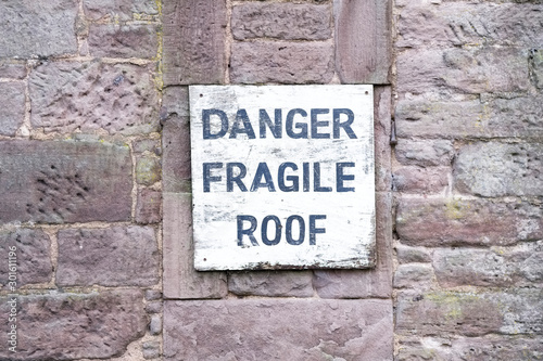 Danger fragile roof sign on wall at farm house