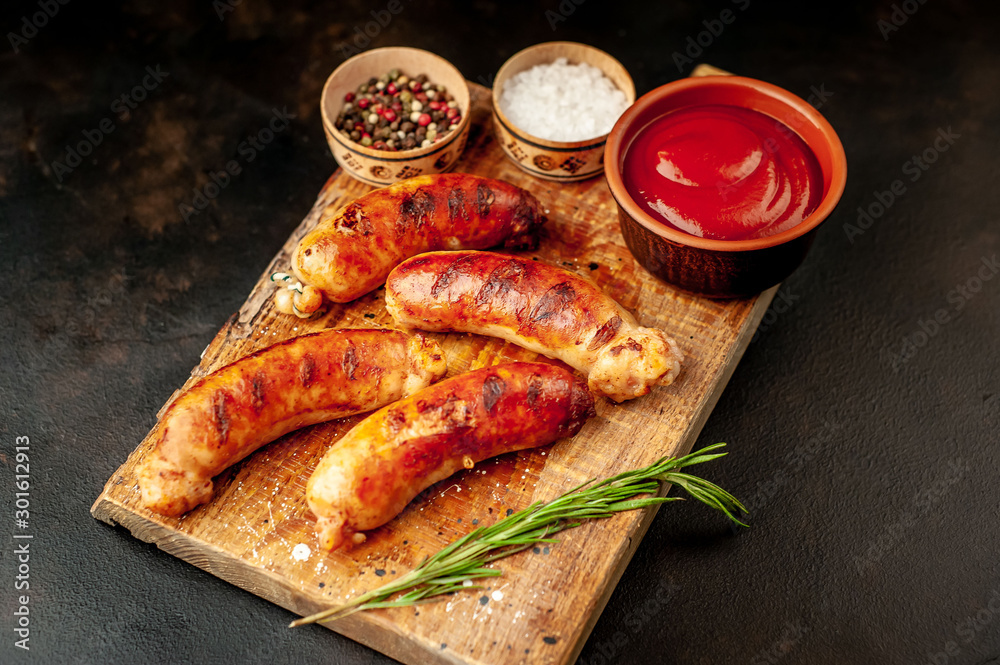 Grilled sausages with spices, ketchup and rosemary on a stone table, ready to eat Grilled sausages with spices, ketchup and rosemary on a stone table, ready to eat