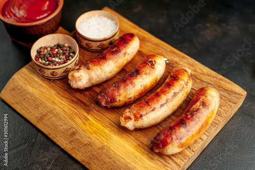 Grilled sausages with spices, ketchup and rosemary on a stone table, ready to eat
