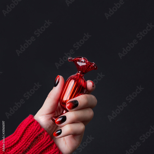 Female hand with red black ombre gradient nails in sweater