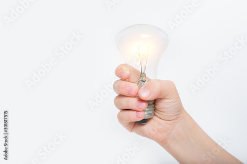 Glowing incandescent lamp in a child's hand on a light background