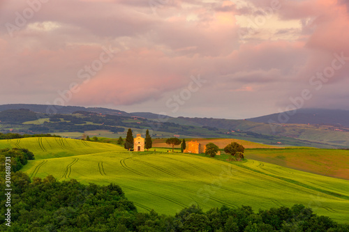 Sunset landscapes in Chapel Vitaleta with green grassland and rolling hills in Tuscany