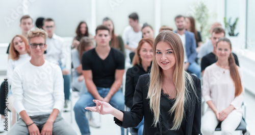 young woman standing in front of an audience in a conference room