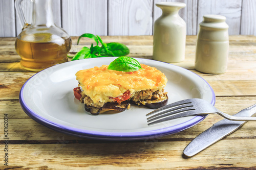 Delicious meat casserole with eggplant, minced meat, tomato, bechamel sauce and cheese. Greek moussaka on rustic wooden background. Selective focus photo