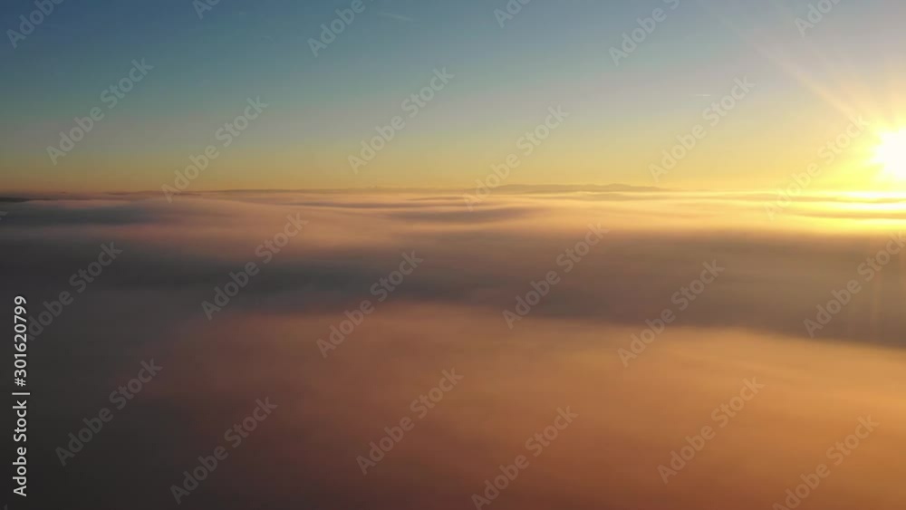 Dreamy drone shot above the fluffy clouds with the sunrise on the background 4K