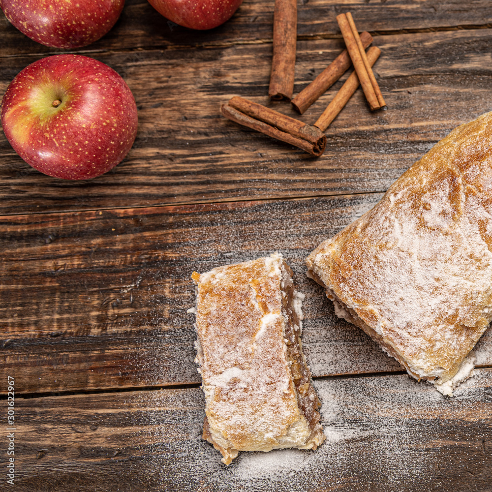Fototapeta premium Traditional apple strudel with powdered sugar on wooden rustic background