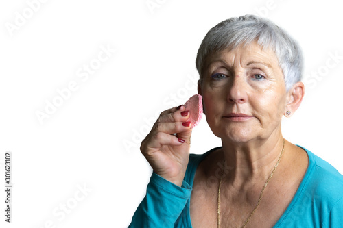 older White haired woman smiling with makeup sponge in her hand on isolated White backhground photo