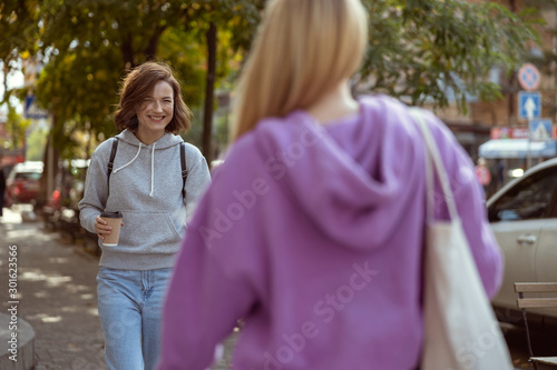Positive delighted brunette female meeting her friend