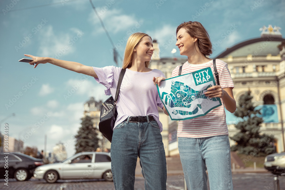 Positive delighted girls walking together with map