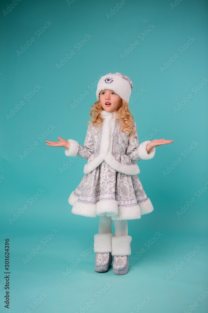 little blonde girl smiling in snow maiden costume isolate on blue background, baby catches snowflakes