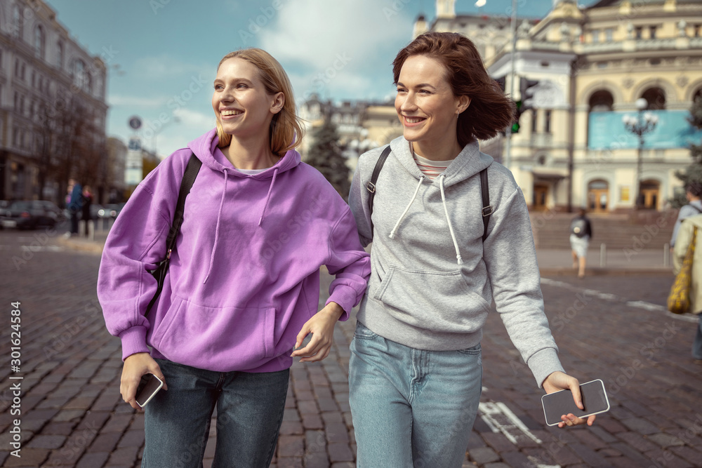Cheerful young females walking around the city
