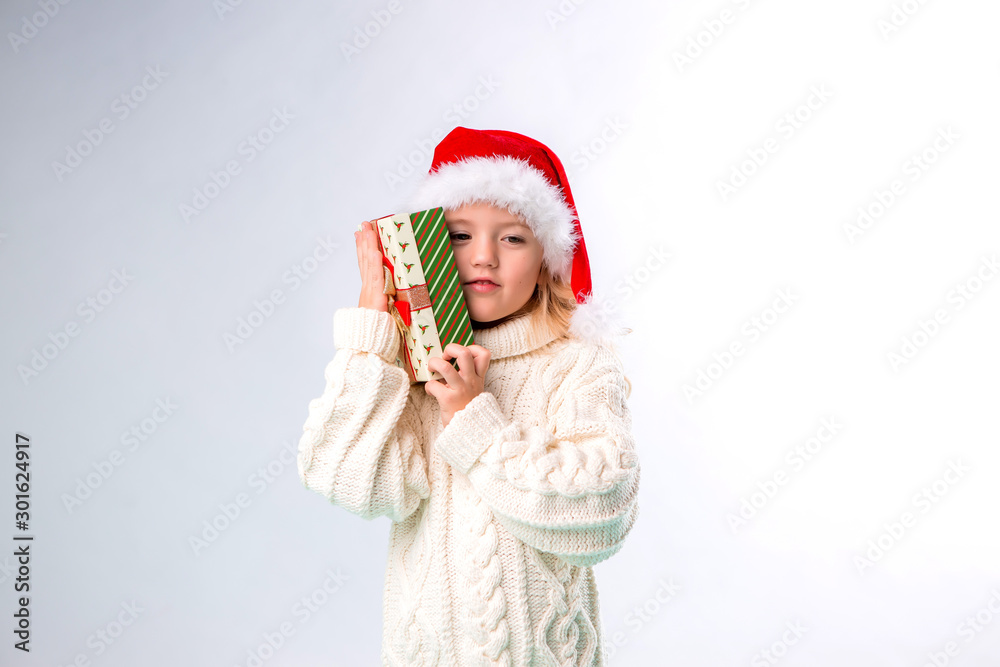 little blonde girl in Santa hat holding gift box, isolate on white background, space for text little blonde girl in Santa hat holding gift box, isolate on white background, space for text