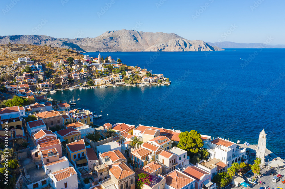 Aerial panoramic view on beautiful Greek houses on island hills, yacht sea port, tourist ferry boat at Aegean Sea bay. Greece islands holiday vacation tours trip