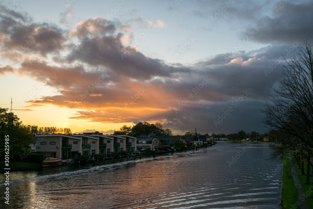 Colorful clouds over the water of the Rhine in Holland at sunset