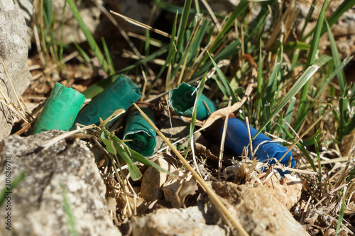 Bossoli in plastica di cartucce a pallini di fucile lasciati nei campi dai cacciatori photo