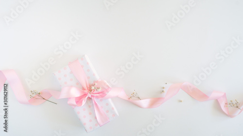 gift box for woman - polka dot paper, pink bow, little flowers. Flat lay or top view. © shapovalphoto