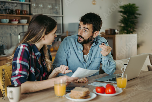 Young couple arguing while having problems with their home finances at dining table