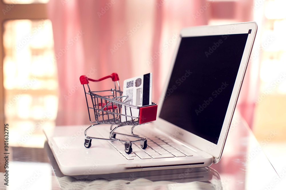 Shopping trolley stays on the laptop. Online shopping concept