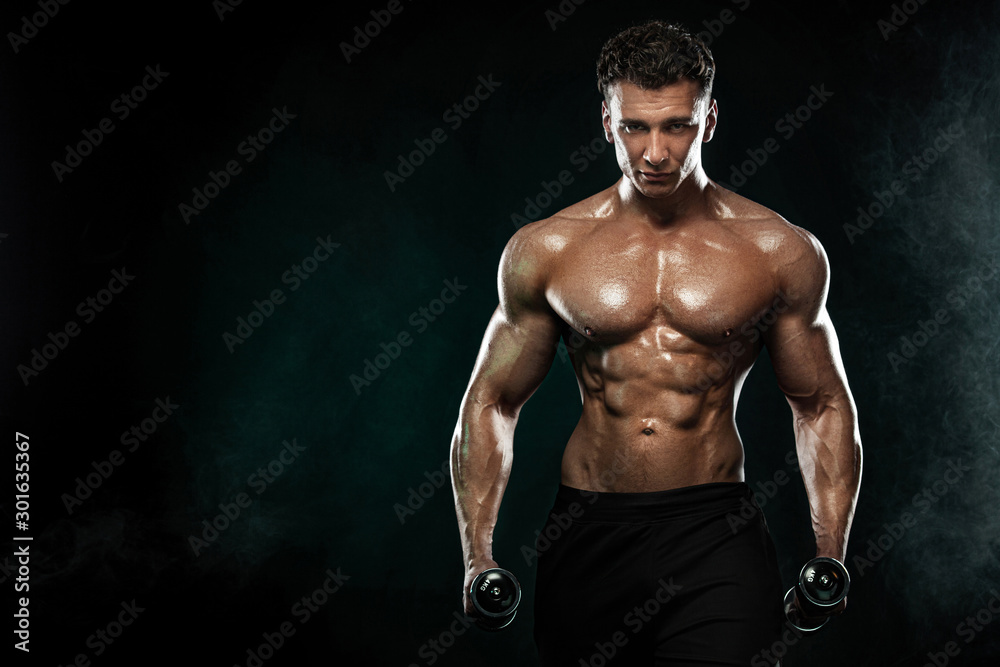 Fototapeta premium Strong and fit man bodybuilder. Sporty muscular guy with dumbbells. Sport and fitness motivation. Individual sports recreation.