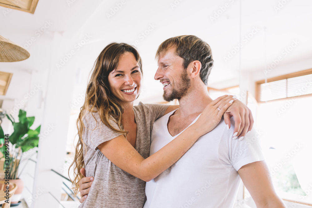 Half length portrait of cheerful positive Caucasian woman hugging lovely husband during leisure day togetherness feeling good from dearness, carefree married pair smiling during honeymoon mood Half length portrait of cheerful positive Caucasian woman hugging lovely husband during leisure day togetherness feeling good from dearness, carefree married pair smiling during honeymoon mood
