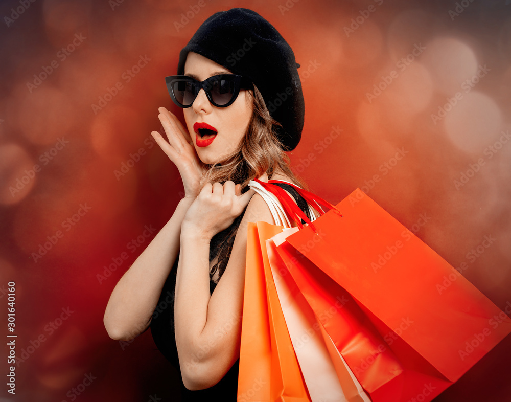 Εκτύπωση καμβά Young woman in black dress with shopping bags on red background