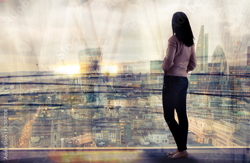 Young woman looking over the City of London at sunset. Beautiful city background in gentle light. Future  freedom  business success and new opportunity concept