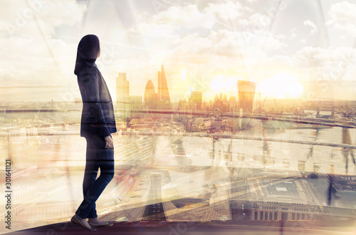 Young woman looking over the City of London at sunset. Beautiful city background in gentle light. Future  freedom  business success and new opportunity concept