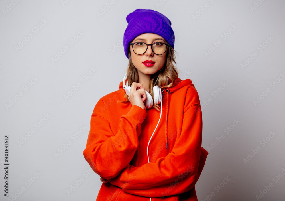 Style girl in orange hoodie and purple hat with headphones Style girl in orange hoodie and purple hat with headphones