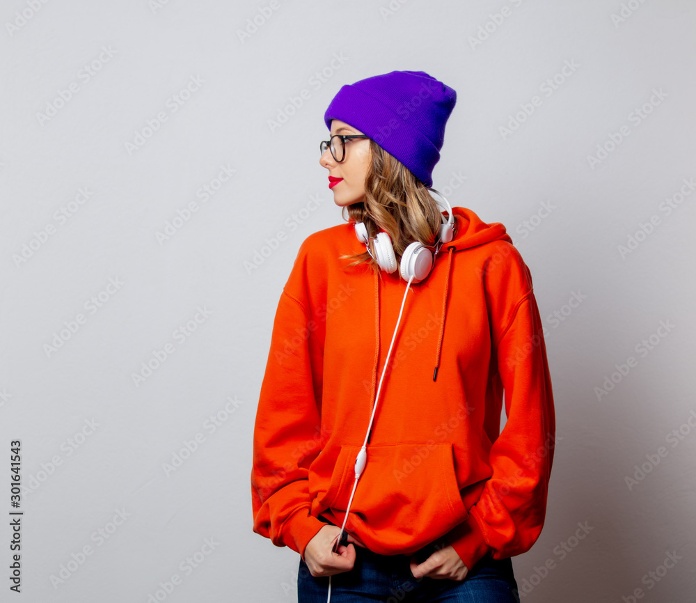 Style girl in orange hoodie and purple hat with headphones