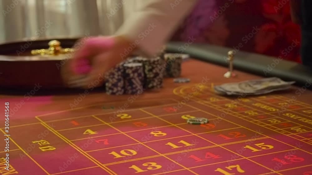 Players collect their winnings and make new bets in the casino. The player exchanges money with the dealer for playing chips. Roulette table layout in low light Players collect their winnings and make new bets in the casino. The player exchanges money with the dealer for playing chips. Roulette table layout in low light