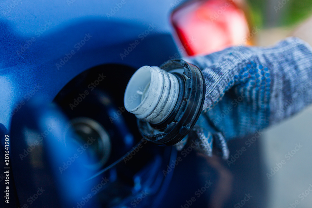 Lid is in the hands of the man of the fuel tank neck. Man hand in