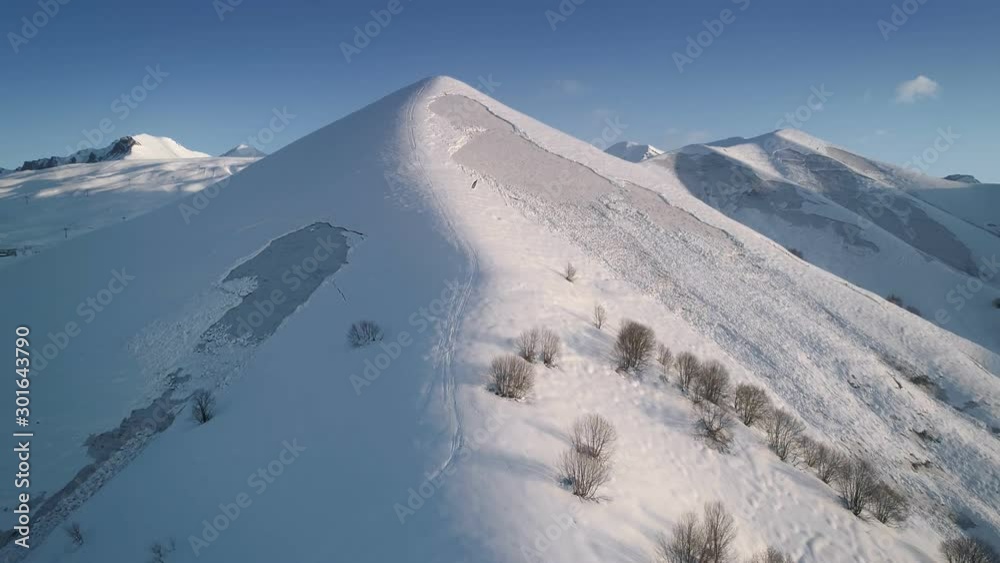 Beautiful Winter mountains in soft morning light. Aerial flight above majestic snowy mountains in winer