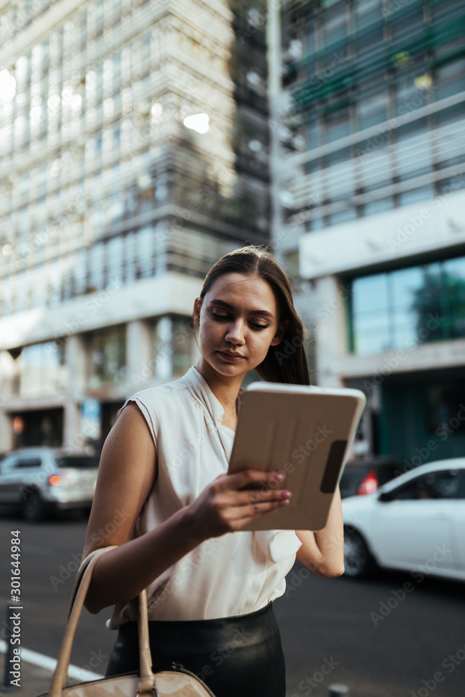 girl satisfied pursed lips looking at tablet pc outdoors