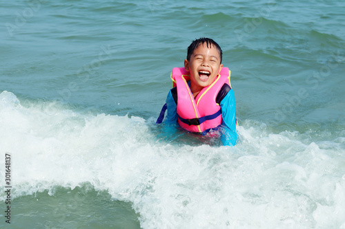 Happy boy playing sea water in the sea. Asian child having fun outdoors. concept of lifestyle summer and vacation. © Janthana