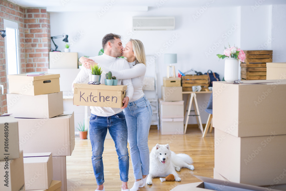 Fototapeta premium Young beautiful couple with dog moving cardboard boxes at new home