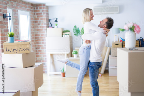 Young beautiful couple hugging at new home around cardboard boxes