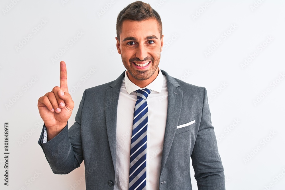 Young handsome business man wearing suit and tie over isolated background showing and pointing up with finger number one while smiling confident and happy. Young handsome business man wearing suit and tie over isolated background showing and pointing up with finger number one while smiling confident and happy.