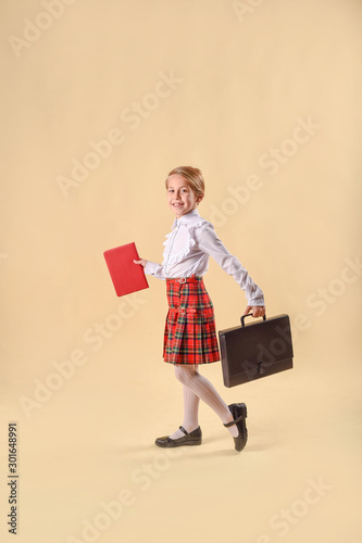 Little girl smile and holding folders.runs and laughs emotionally. Without milk tooth. Red and black folder in the hands.yellow background in the studio. Concept of business, money and success