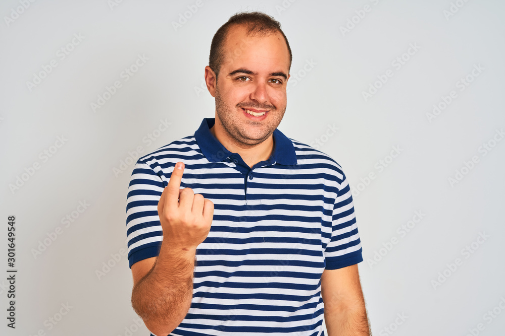 Young man wearing casual striped polo standing over isolated white background Beckoning come here gesture with hand inviting welcoming happy and smiling Young man wearing casual striped polo standing over isolated white background Beckoning come here gesture with hand inviting welcoming happy and smiling