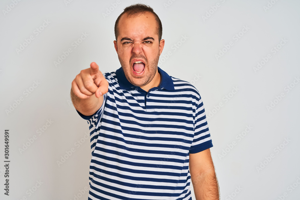Young man wearing casual striped polo standing over isolated white background pointing displeased and frustrated to the camera, angry and furious with you Young man wearing casual striped polo standing over isolated white background pointing displeased and frustrated to the camera, angry and furious with you