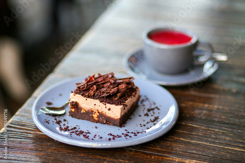 A metal teapot with rose tea in a restaurant. Tea party with chocolate dessert in a cafe. Vitamin raspberry tea with mint and cheesecake. Sweets  desserts with a hot drink.Gray dishes and wooden table