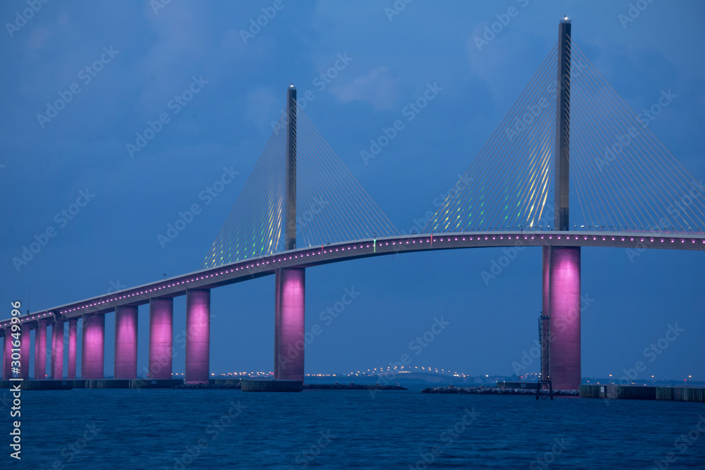 Closeup of the iconic Sunshine Skyway Bridge spanning the wide mouth of beautiful Tampa Bay in central Florida lit up in pink LED lights to commemorate Breast Cancer Awareness Month. Closeup of the iconic Sunshine Skyway Bridge spanning the wide mouth of beautiful Tampa Bay in central Florida lit up in pink LED lights to commemorate Breast Cancer Awareness Month.