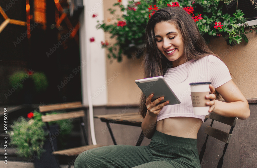 Obraz premium Beautiful woman using tablet and drink coffee sitting in street cafe.