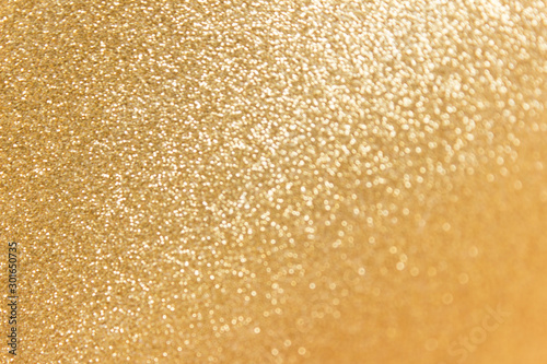 Abstract festive golden glitter sparkling background with defocused bokeh smudged effect.