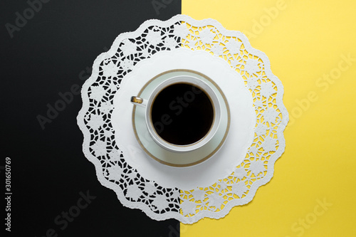 Top view of one single cup of coffee on napkin servette standing on yellow black background. photo