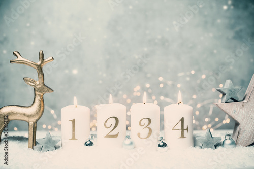 Advent candles 1  2 3 4 in front of concrete background in the snow with colorful lights and gray trees
