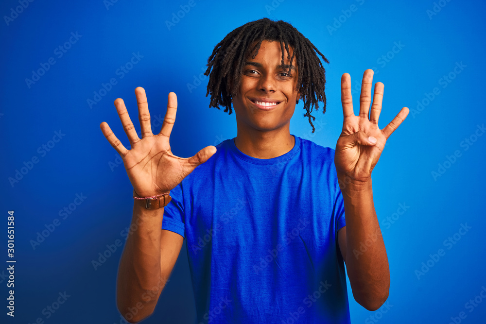 Afro american man with dreadlocks wearing t-shirt standing over isolated blue background showing and pointing up with fingers number nine while smiling confident and happy. Afro american man with dreadlocks wearing t-shirt standing over isolated blue background showing and pointing up with fingers number nine while smiling confident and happy.