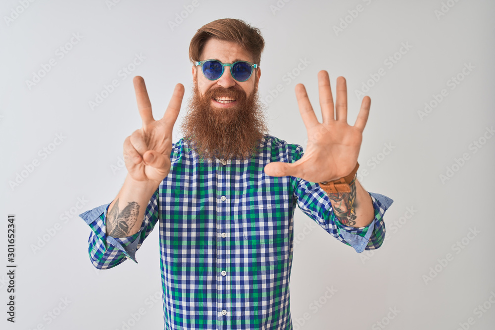 Young redhead irish man wearing casual shirt and sunglasses over isolated white background showing and pointing up with fingers number seven while smiling confident and happy. Young redhead irish man wearing casual shirt and sunglasses over isolated white background showing and pointing up with fingers number seven while smiling confident and happy.